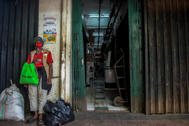 Seorang laki-laki mengenakan masker dan berdiri di depan toko yang tutup akibat merebaknya wabah virus corona di Pasar Minggu, Jakarta. Foto: Galih Pradipta/ANTARA FOTO
