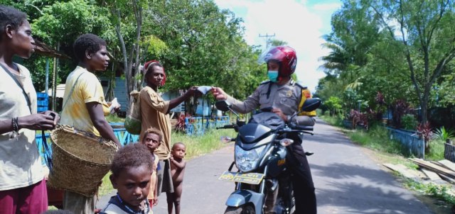 Bhabinkamtibmas sambangi warga di Kampung Rawa Biru Meruke sambil membagikan masker. (Dok: Polda Papua)