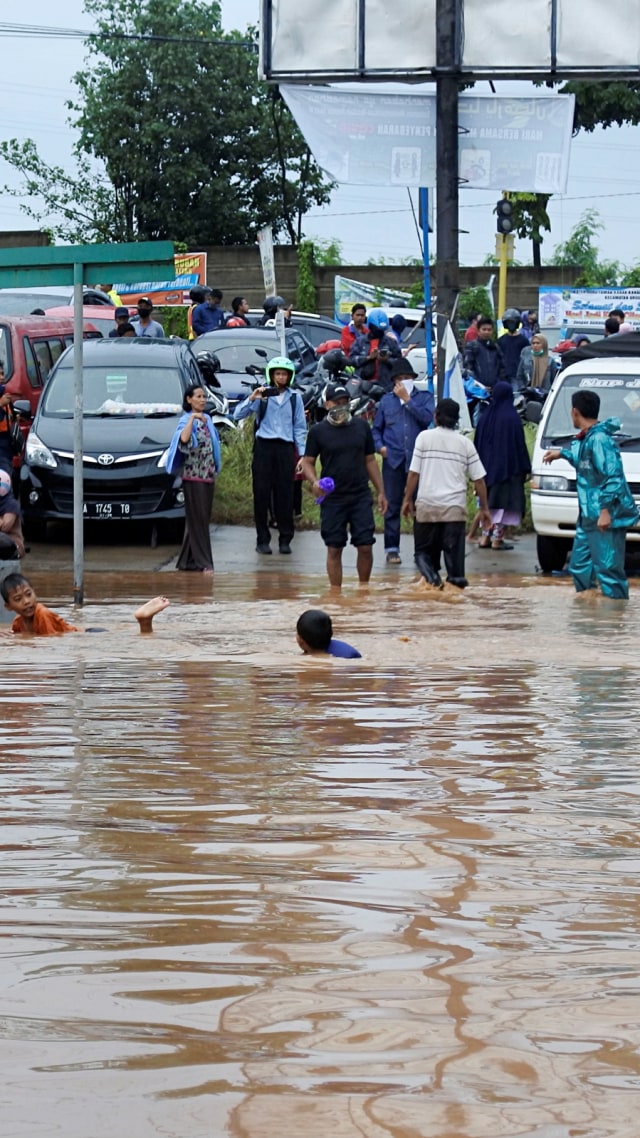 Sejumlah warga berdiri menunggu banjir surut di Kotasari, Grogol, Cilegon, Banten, Senin (4/5). Foto: ANTARA FOTO/Asep Fathulrahman