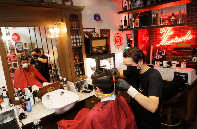 Seorang pelanggan yang mengenakan masker saat melakukan perawatan rambut di Thessaloniki, Yunani, Senin (4/5). Foto: REUTERS/MURAD SEZER