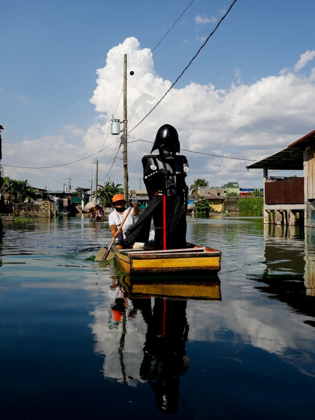 Seorang perwira desa mengenakkan pakaian Darth Vader mengendarai perahu untuk mengirimkan makanan kepada penduduk di Malibon, Metro Manila, Filipina.  Foto: REUTERS / Eloisa Lopez