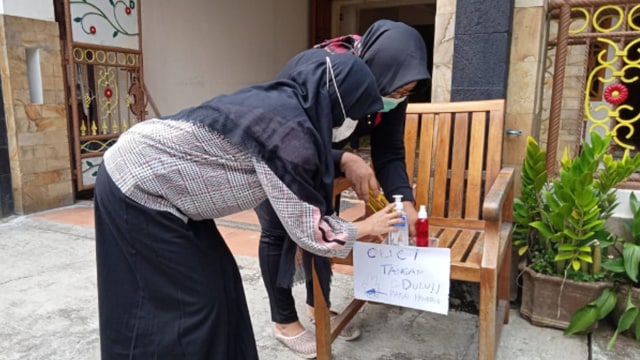Pelayat saat menggunakan hand sanitizer sebelum masuk rumah duka. (Fernando Fitusia)