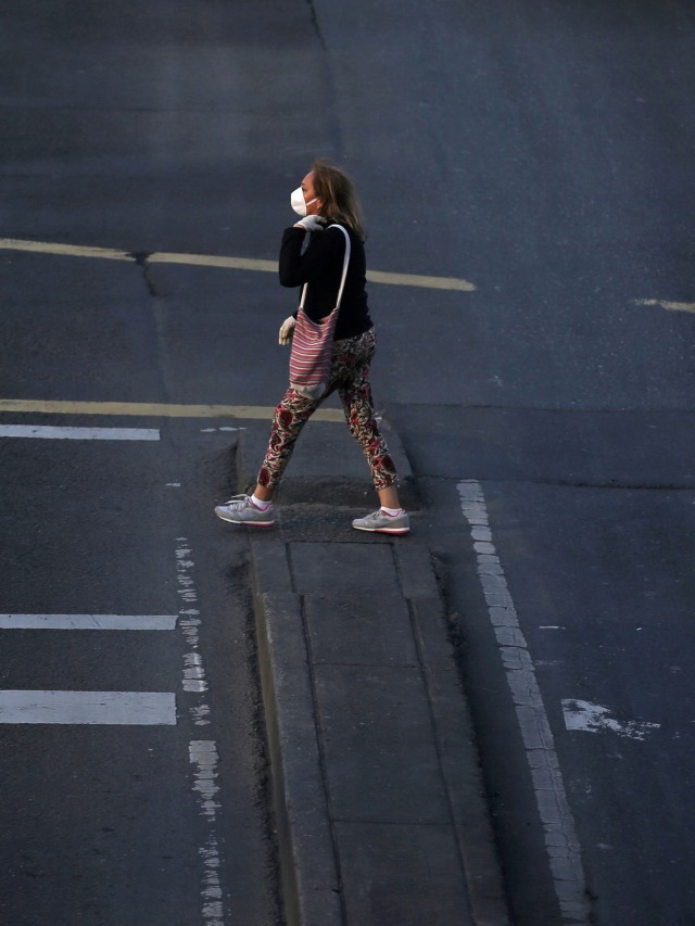 Seorang wanita menggunakan masker berjalan di Bogota, Kolombia. Foto: REUTERS / Luisa Gonzalez