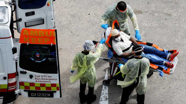 Petugas medis membantu pekerja migran naik ambulans di Singapura. Foto:  REUTERS / Edgar Su