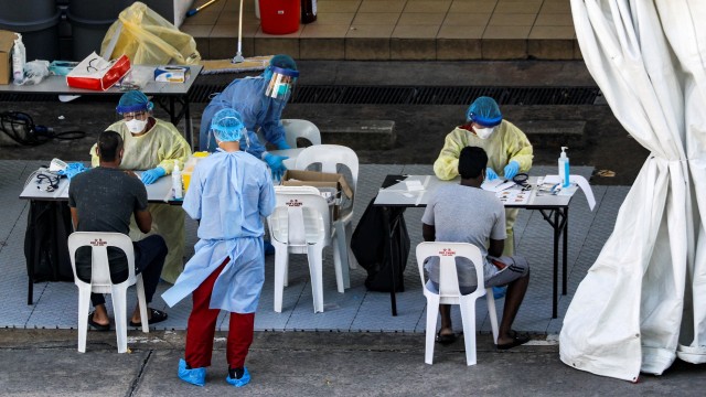 Petugas medis melakukan test swab pada  pekerja migran di Singapura. Foto:  REUTERS / Edgar Su