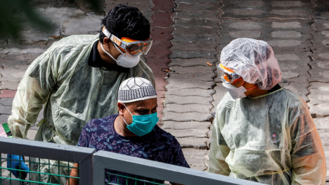 Petugas medis membawa pekerja migran di Singapura. Foto:  REUTERS / Edgar Su