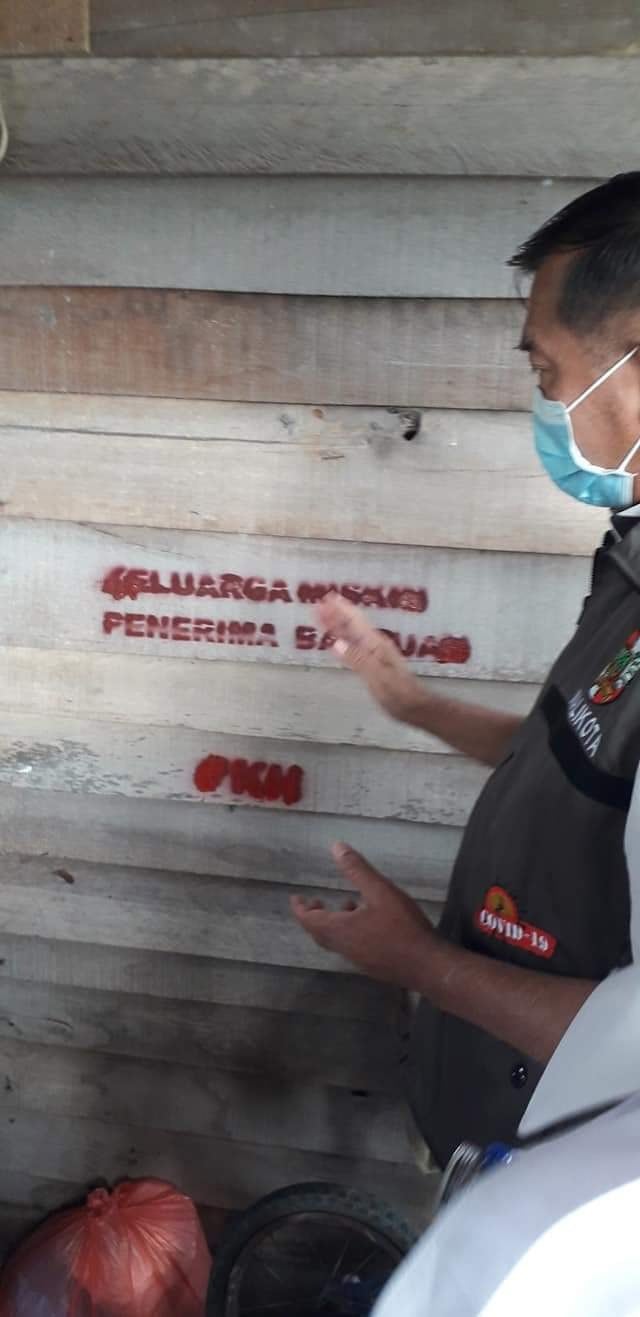WALI Kota Pekanbaru, Firdaus, saat memasang tanda "Keluarga Miskin Penerima Bantuan" di dinding rumah warga, Rabu, 6 Mei 2020.  