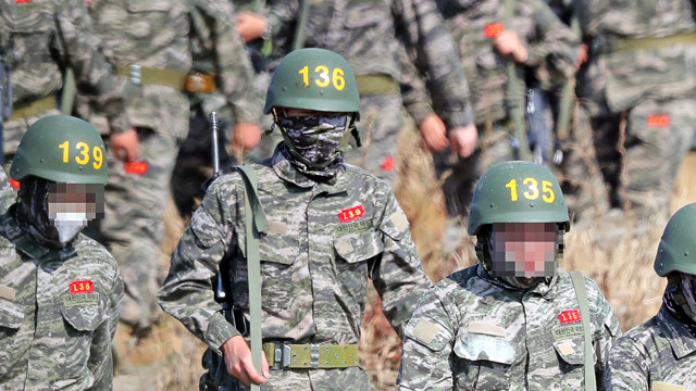 Son Heung Min dengan seragam militer membawa senapan.jpg