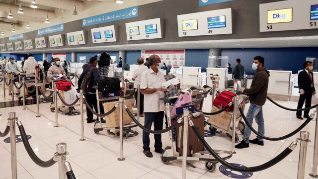 Warga Negara India mengunakan masker berdiri dalam antrian chek-in saat penerbangan pertama dari Dubai ke India di Bandara Internasional Dubai, UEA. Foto: Bandara Internasional Dubai / via REUTERS