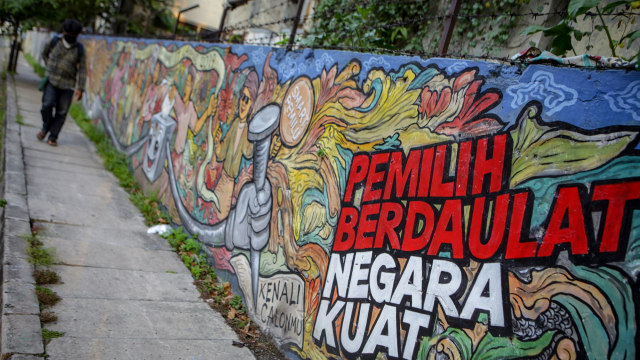 Warga melintas di depan mural bertema pemilihan umum di kawasan Pasar Anyar, Kota Tangerang, Banten. Foto: ANTARA FOTO/Fauzan