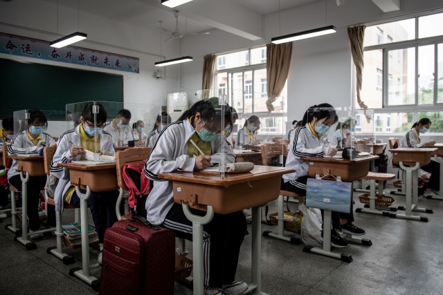 Siswa sekolah menengah atas belajar dengan menggunakan partisi plastik di runagan kelas di Wuhan, Hubei, China. Foto: AFP/STR