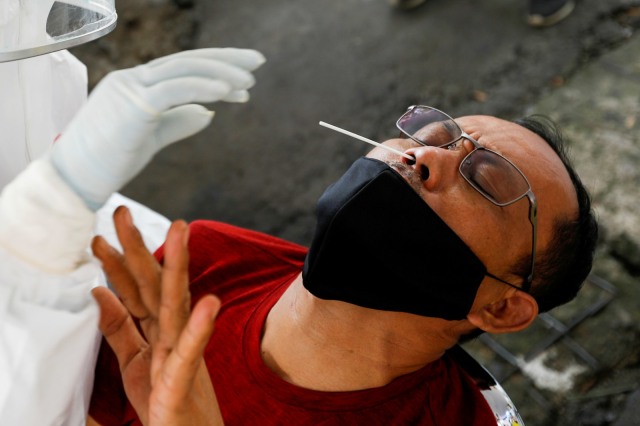 Petugas medis mengambil sampel cairan dari hidung dan tenggorokan warga saat mengikuti tes swab di pasar tradisional di Bogor, Jumat (8/5). Foto:  REUTERS / Willy Kurniawan