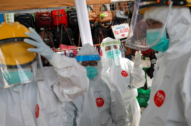 Petugas medis dengan APD lengkap bersiap untuk mengambil sampel swab dari warga di pasar tradisional. Foto:  REUTERS / Willy Kurniawan