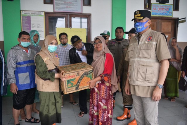 Plt Gubernur Aceh Nova Iriansyah yang datang bersama istrinya menyerahkan bantuan logistik kepada pengungsi saat meninjau posko korban banjir di Aceh Besar, Jumat (8/5) sore. Foto: Dok. Humas Setda Aceh