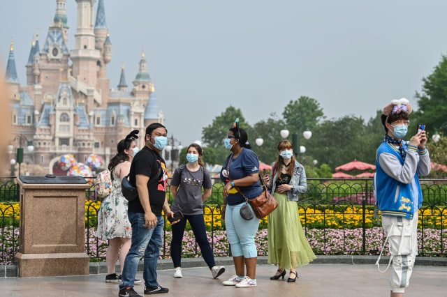 Warga mengenakan masker saat mengunjungi taman hiburan Disneyland di Shanghai, Senin (11/5). Foto: Hector RETAMAL / AFP