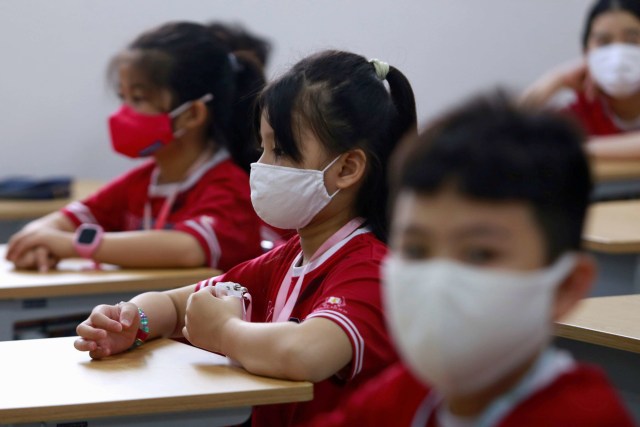 Para siswa sekolah dasar yang mengenakan masker saat hari pertama masuk sekolah setelah lockdown. Foto: REUTERS/Yen Duong