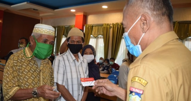 Wali Kota Palu Hidayat saat menyerahkan secara simbolis kartu sembako bantuan Kemensos RI kepada keluarga penerima manfaat (KPM) di Palu. Foto: Istimewa