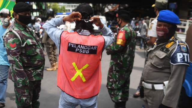 Seorang warga yang terjaring razia penindakan pelanggaran aturan PSBB oleh Satpol PP menjalani hukuman dengan cara membersihkan sampah di Tanah Abang, Jakarta. Foto: ANTARA FOTO/Akbar Nugroho Gumay