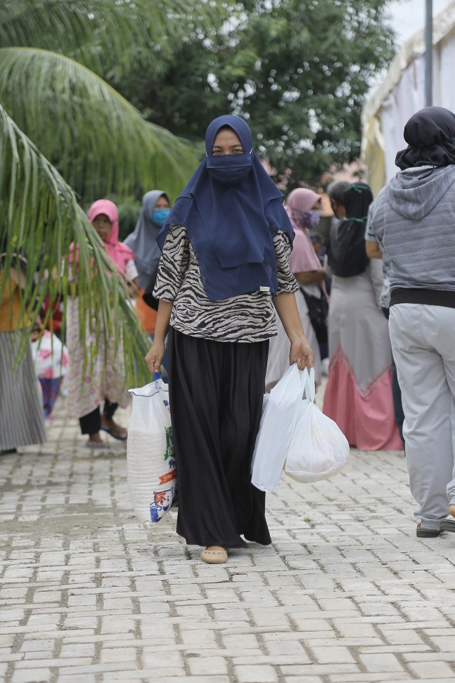 Seorang warga menjinjing paket bahan pokok yang dibeli di pasar murah bertempat di Peukan Bada, Aceh Besar, Rabu (13/5). Foto: Abdul Hadi/acehkini