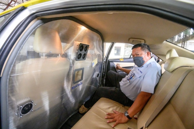 Seorang pengemudi taksi menunjukkan penghalang sekat baru yang dibuat oleh aeronautika militer Thailand, di Bangkok, Thailand. Foto: AFP/Mladen ANTONOV