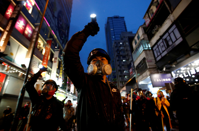 Demonstran yang memprotes RUU ekstradisi yang diusulkan mengarahkan senter mereka ke arah polisi anti huru hara di jalan-jalan Hong Kong, Cina, (25/8/2019). Foto: REUTERS/Willy Kurniawan