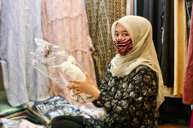 Seorang pedagang di Kota Banda Aceh memakai masker saat berjualan pakaian di Pasar Aceh, Minggu (3/5). Foto: Suparta/acehkini