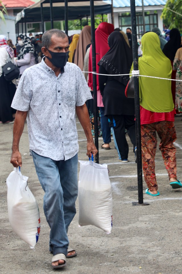 Warga menjinjing karung beras yang dibeli di pasar murah di wilayah Kota Banda Aceh. Foto: Suparta/acehkini