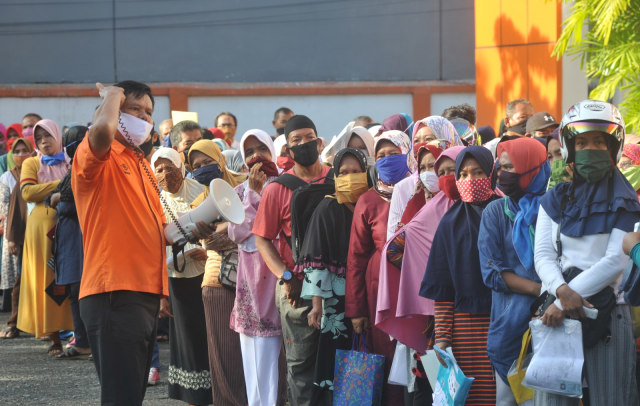 Petugas mengingatkan warga agar menjaga jarak saat mengantre penyaluran bansos tunai Kemensos, di Kantor Pos Khatib Sulaiman, Padang, Jumat (15/5). Foto: ANTARA FOTO/Iggoy el Fitra