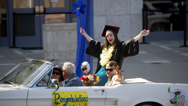 Seorang lulusan dari California State University San Marcos merayakan saat berpartisipasi dalam parade mobil di San Marcos, California, AS. Foto: REUTERS/Mike Blake
