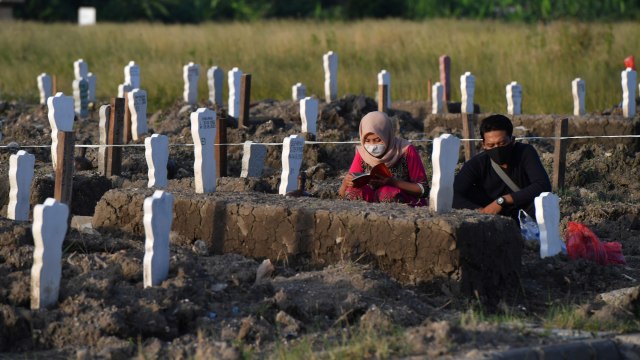 Peziarah berdoa di pemakaman khusus kasus COVID-19 di Tempat Pemakaman Umum (TPU) Keputih, Surabaya, Jawa Timur, Sabtu (16/5/2020). Foto: ANTARA FOTO/Zabur Karuru