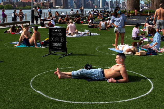 Sejumlah warga menerapkan social distancing saat bersantai di Domino Park, Brooklyn, New York, AS, Sabtu (16/5). Foto: Reuters/Eduardo Munoz