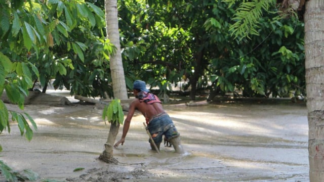 Kondisi terkini. Tampak seorang warga kesulitan berjalan karena lumpur yang menggenangi pemukiman penduduk pasca banjir bandang terjadi di Desa Poi, Sigi, pada Jumat (15/5).