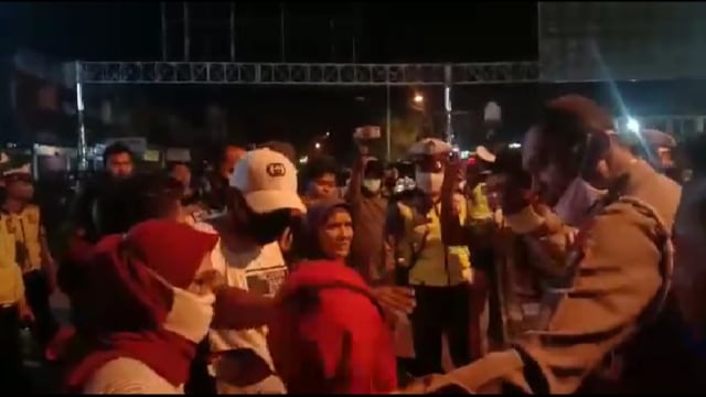 ANGGOTA Kepolisian berdialog dengan warga dan pedagang yang menolak pemberlakuan jam malam selama penerapan PSBB di Kota Dumai, Riau. 