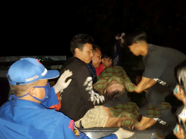 Petugas dan warga mengevakuasi jenazah korban tenggelam di pantai Widuri. 