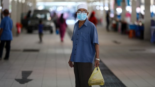 Seorang pria menggunakan masker memegang plastik di Pasar Malam Gadong, Bandar Seri Begawan, Brunei. Foto: AFP/Dean KASSIM