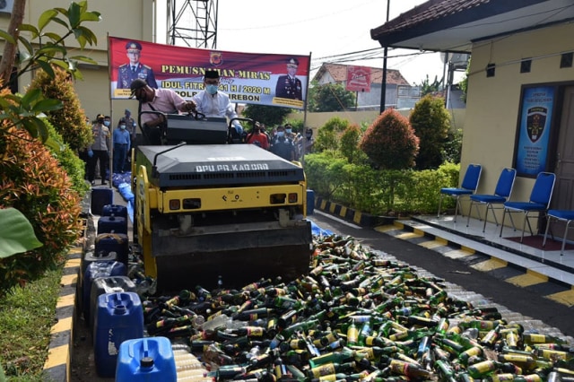 Belasan ribu botol miras dihancurkan menggunakan kendaraan berat vibro roller atau stum di halaman Mapolresta Cirebon, Jumat (22/5/2020). (Juan)