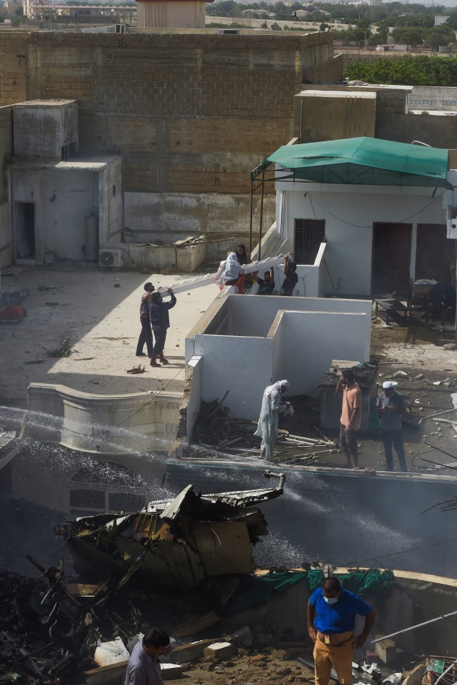 Petugas penyelamat mengevakuasi korban yang terluka dari lokasi setelah sebuah pesawat Pakistan International Airlines jatuh di lingkungan perumahan di Karachi. Foto: AFP/ASIF HASSAN