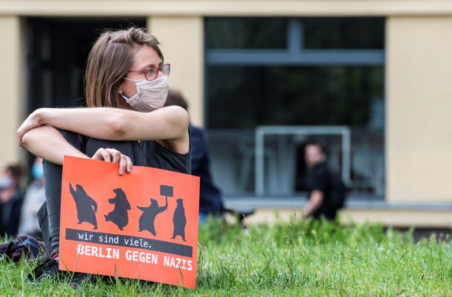 Seorang demonstran yang mengenakan masker memegang poster bertuliskan "Kami banyak, Berlin melawan Nazi" saat Protes penanganan corona di Berlin, Jerman. Foto: John MACDOUGALL / AFP