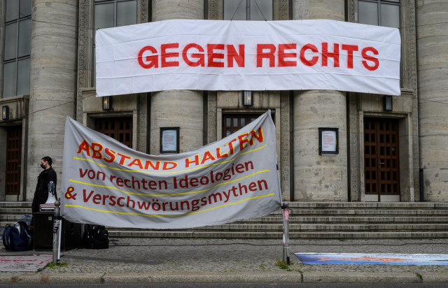Spanduk yang bertuliskan "Menjauhkan diri dari ideologi sayap kanan dan mitos konspirasi" terlihat saat Protes penanganan corona di Berlin, Jerman. Foto: John MACDOUGALL / AFP
