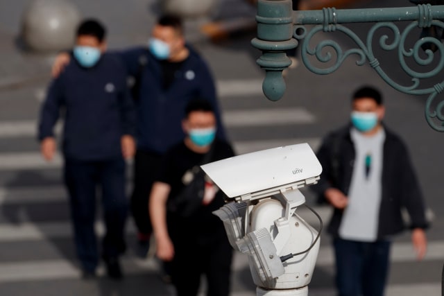 Kamera pengintai CCTV terpasang ketika sejumlah warga berjalan di Beijing, China. Foto: REUTERS / Thomas Peter