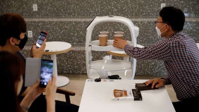 Sebuah robot mengantarkan pesanan kopi ke pelanggan di sebuah kafe di Daejeon, Korea Selatan, Senin (25/5). Foto: REUTERS/Kim Hong-Ji