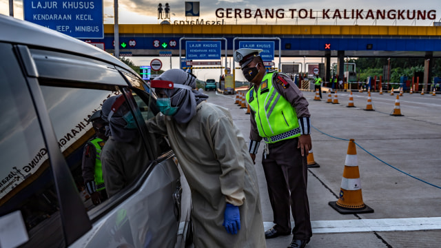 Petugas kesehatan memeriksa suhu pengendara mobil saat penyekatan pemudik di Gerbang Tol Kalikangkung, Semarang, Jawa Tengah, Selasa (26/5). Foto: Antara/Aji 