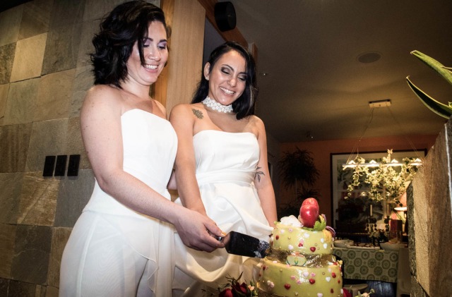 Pasangan pengantin baru sesama jenis Alexandra Quiros dan Dunia Araya memotong kue pernikahan mereka di Heredia, Kosta Rika. Foto: AFP/EZEQUIEL BECERRA