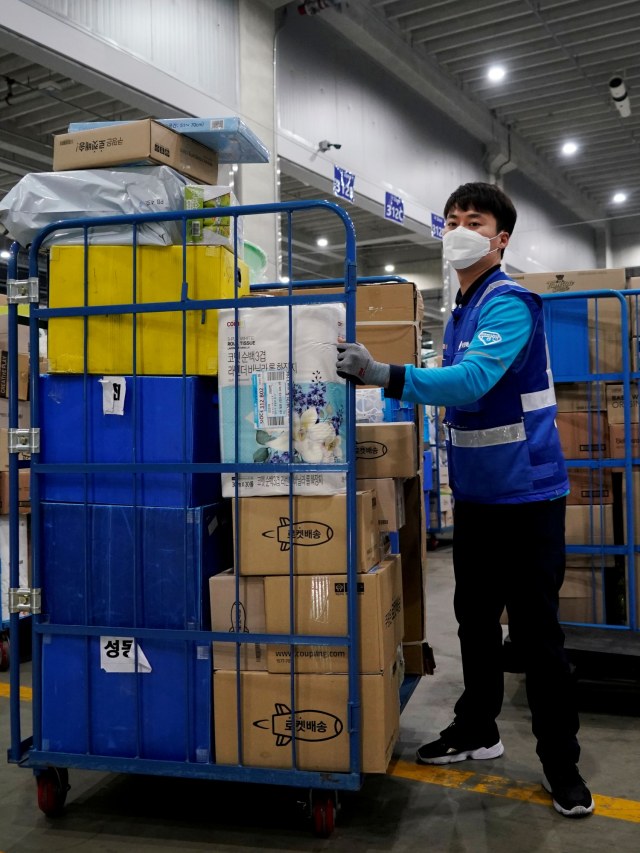 Petugas pengiriman menggunakan masker memuat paket sebelum mengirimkannya di Incheon, Korea Selatan.
 Foto: REUTERS / Kim Hong -Ji