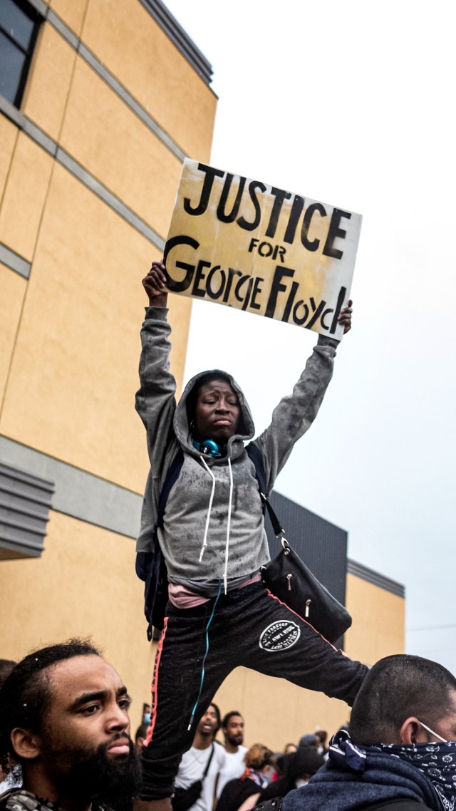 Massa menunjukkan poster dalam aksi protes terkait pembunuhan pria kulit hitam oleh aparat di Minneapolis, AS, Selasa (26/5). Foto: Richard Tsong-Taatarii/Star Tribune via AP