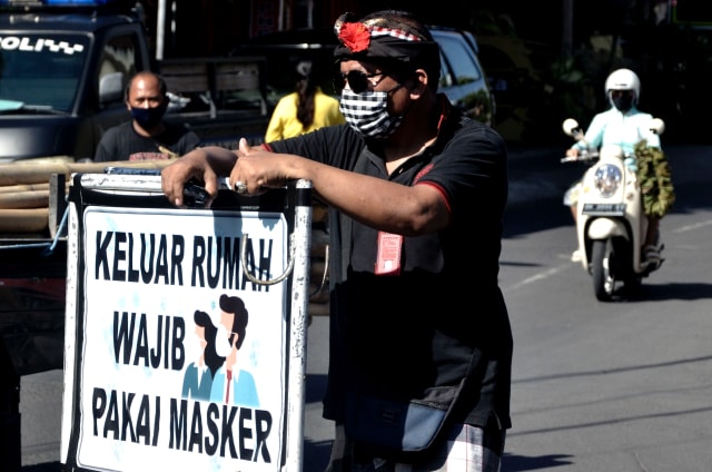 Pecalang atau petugas keamanan adat Bali melakukan pengawasan terkait pencegahan virus corona. Foto: Antara/Fikri Yusuf
