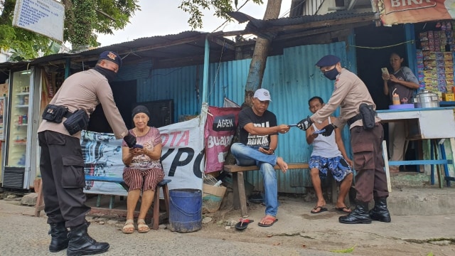 Anggota Brimob Polda Kaltim memberikan masker kepada warga saat menggelar patroli dialogis guna pencegahan penyebaran virus corona. Foto: Dok. Polda Kalimantan Timur