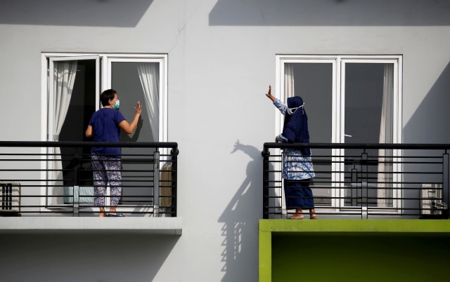 Pasien yang terinfeksi virus corona menyapa usai mengikuti senam pagi di balkon Rumah Singgah Karantina, Kabupaten Tangerang, Banten, Selasa (28/5).  Foto: REUTERS/WIlly Kurniawan