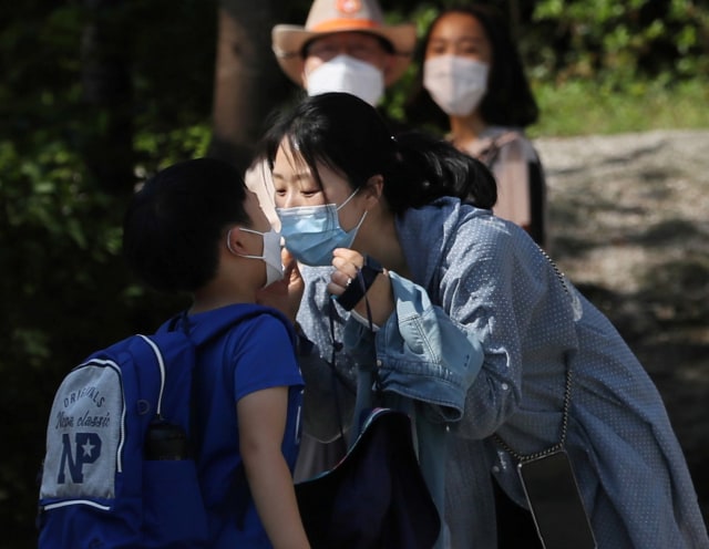 Seorang ibu mencium anaknya di sebuah sekolah dasar di Seoul, Korea Selatan, Rabu (27/5). Foto: REUTERS