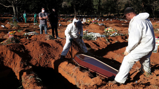 Petugas menggunakan pakaian pelindung mengubur peti jenazah pasien yang terinfeksi virus corona di pemakaman Vila Formosa, Sao Paulo, Brasil. Foto: REUTERS / Amanda Perobelli